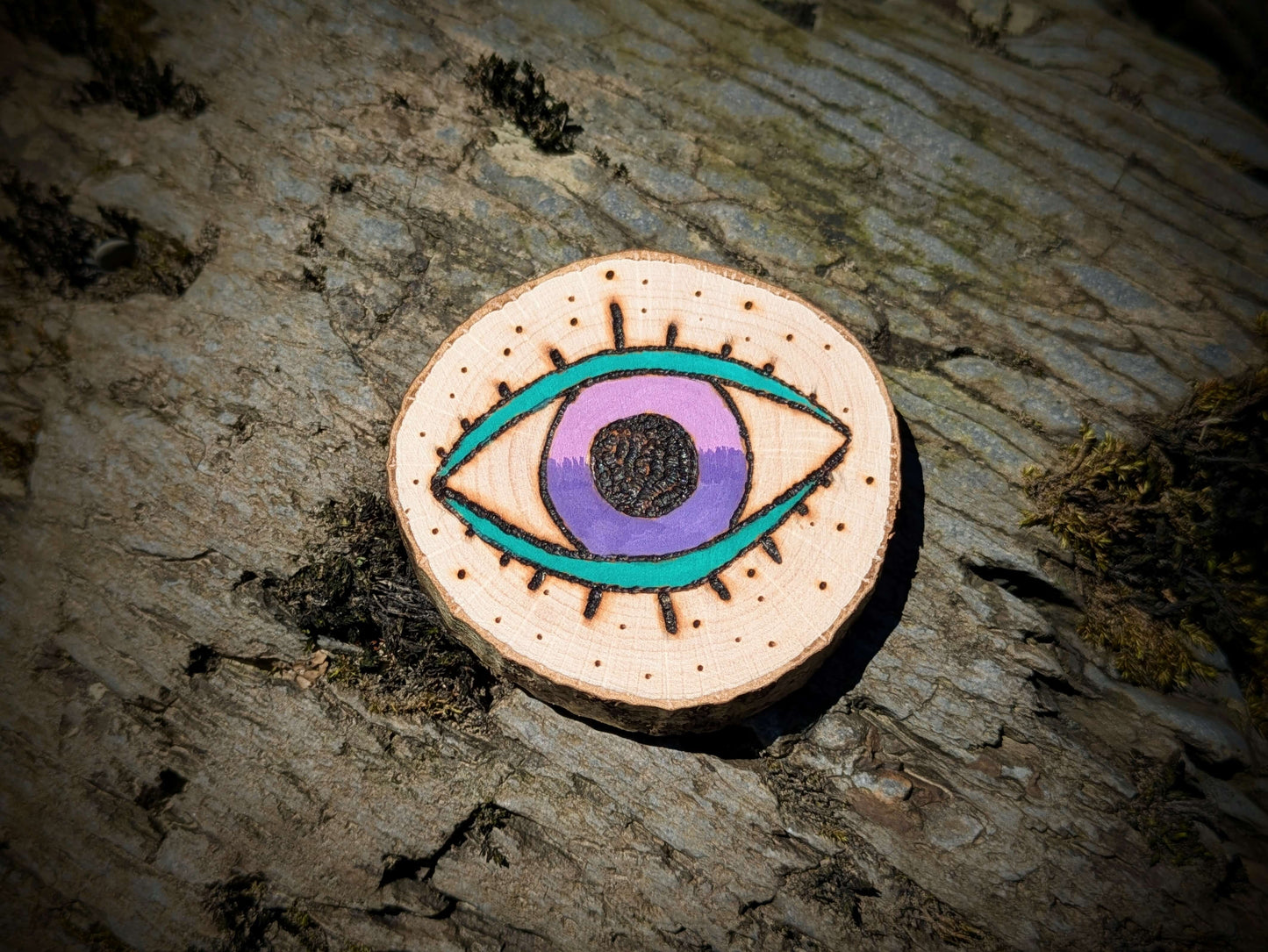 A picture of an ethically sourced Hematite crystal necklace, with incense and pyrography/ woodburning round