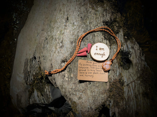 A picture of an ethically sourced Rose Quartz crystal necklace, with incense and pyrography/ woodburning round