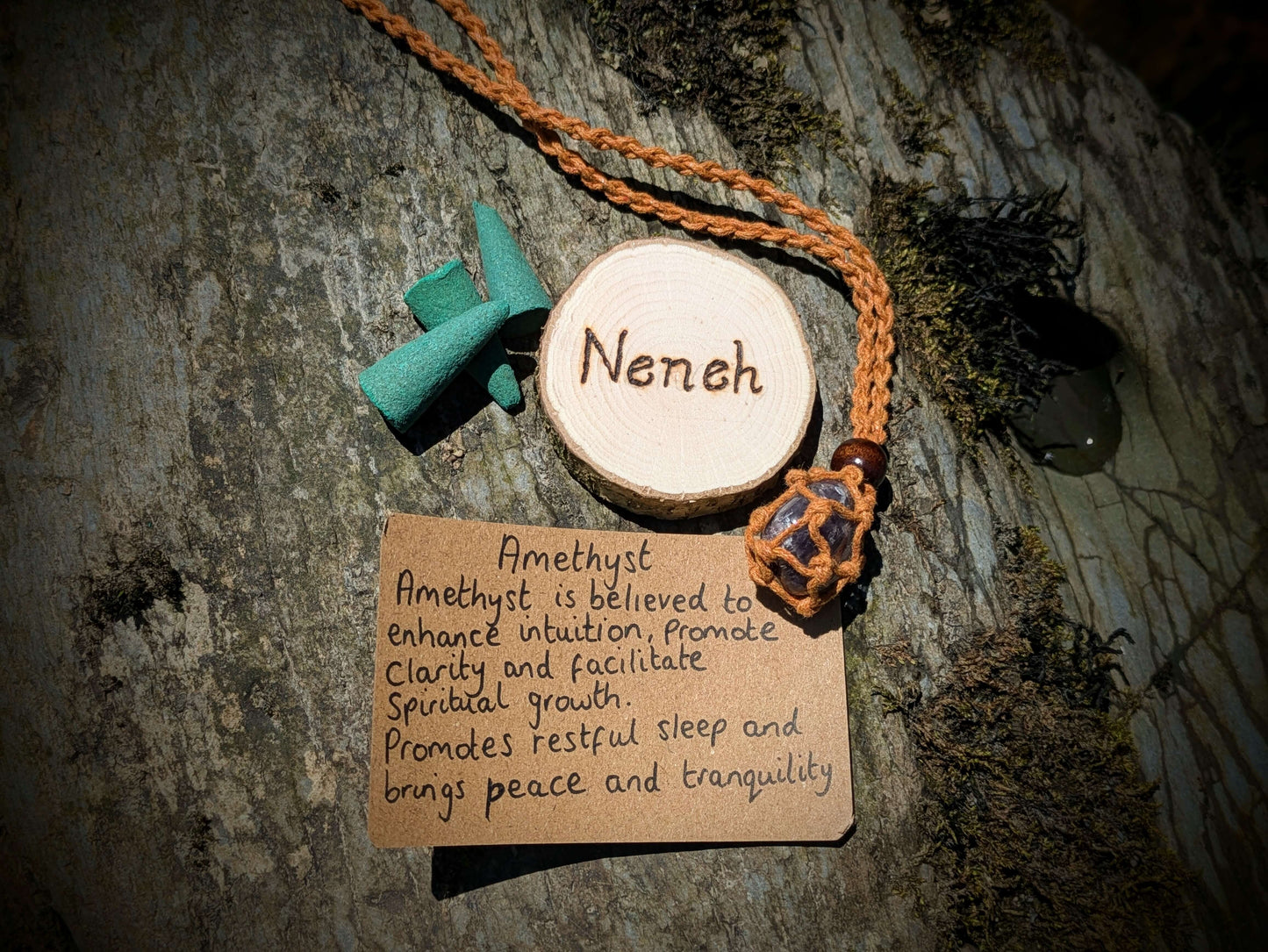 A picture of an ethically sourced Hematite crystal necklace, with incense and pyrography/ woodburning round