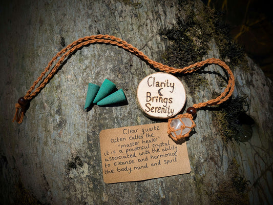 A picture of an ethically sourced Clear Quartz crystal necklace, with incense and pyrography/ woodburning round