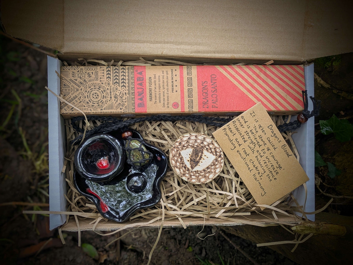 A spiritual wellness item featuring Dragon’s Blood-themed grounding set with crystal-inspired imagery, incense, and ritual accessories in a warm, earthy aesthetic.