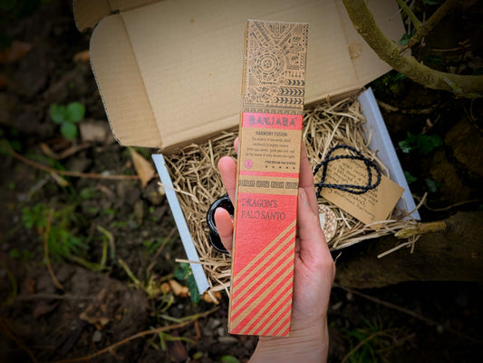 A spiritual wellness item featuring Dragon’s Blood-themed grounding set with crystal-inspired imagery, incense, and ritual accessories in a warm, earthy aesthetic.