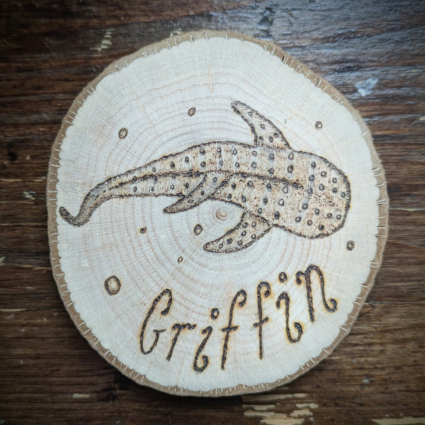 Wooden coaster with a whale shark design and 'Griffin' engraving on a wooden surface